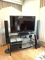 Overall view of Toshiba TV on stand with Sony receiver, subwoofer and two speakers