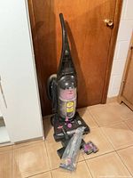 Full view of Bissell CleanView Helix Deluxe upright vacuum with attachments placed in front