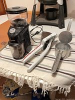 Coffee grinder, two potato ricers on table