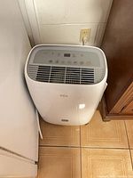 Front view of TCL dehumidifier beside furniture