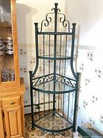 Full view of green metal corner shelving unit with glass shelves