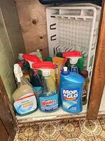 Under-sink cabinet showing multiple cleaning bottles and dishpan