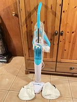 Full view of SteamTek steam mop standing upright with attached cord and pads