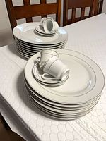 Two stacks of plates with cups and saucers on top, showing dinner and salad plates