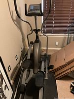 Grey elliptical trainer showing console, pedals, handlebars