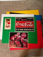 All three Coca-Cola metal signs on colored backers
