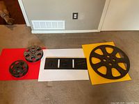 All four items laid out: three film reels of differing sizes and one rectangular plaque.