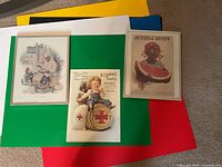 Overall view of three framed advertising prints on colored boards