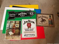 All four whiskey-themed metal signs arranged on floor