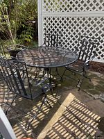 Full view of round mesh table with four chairs on patio