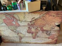 Front view of three-plank wooden wall sign with world map and rope hanger