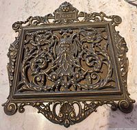 Front view of ornate cast iron paper holder showing full design and size