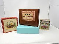 Group shot of four containers: two cigar boxes, teal box, decorative music tin