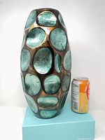 Full view of vase next to soda can for scale showing green-teal ovals and brown glaze