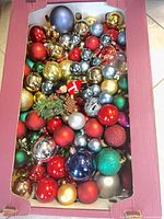 Top view of box filled with assorted round ornaments in various colors and finishes