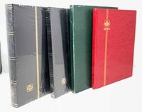 Front view of four stamp albums: two sealed black, one green, one red Canada