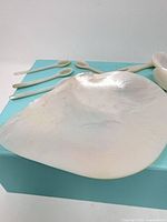 Large polished shell dish and four small spoons