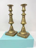 front view of both brass candlestick holders on square bases