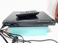 Front and top view of Sony DVD player with remote on top and cables visible