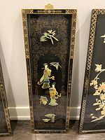 Full view of vertical black lacquer wall panel with inlaid figures and gold border