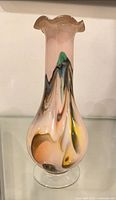 Front view of multicolour art glass vase on glass shelf