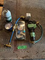 All components laid out: refrigerant can, hoses, gauges, adapter, injection gun