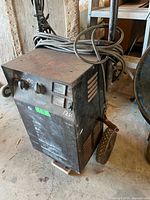 Front view showing charger body, wheels, handle, cords