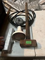 Flood light, sledge hammer, door closer parts on table