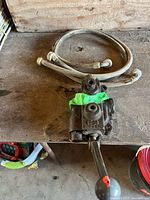 Hydraulic control valve with hose coiled above on workbench