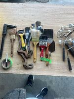 group of paint roller handles, brushes, chain tightener, tape, trowel