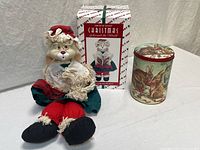 Bunny doll seated next to holiday tin and original box