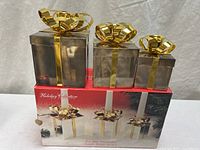 Three candle holders atop original box, showing size differences