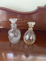 Both glass decanters side by side showing overall form and stoppers