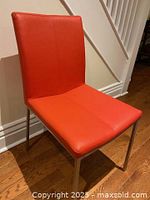 Full view of one red leather dining chair with metal legs