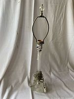 Full view of clear glass column lamp with harp and finial