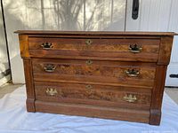 Front view showing three drawers, brass pulls, keyholes, overall style