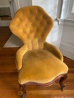 Front view showing tufted back, seat, wooden legs with casters