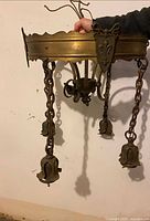 Side view of brass chandelier showing chain-hung light holders