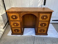 Front view of oak desk showing six drawers, arched kneehole, contrasting drawer fronts