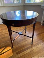 Full view of round side table showing legs, stretcher, casters