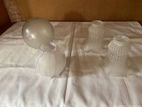 Group of four frosted glass shades displayed on cloth