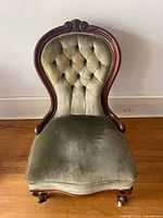 Front view showing upholstery, tufting, cabriole legs on casters