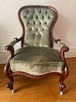 Front view showing full chair, upholstery, carved frame, casters