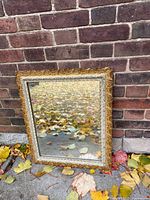 Front view of mirror against brick wall showing ornate gold frame and reflective glass