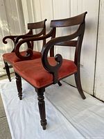 Side view of both chairs showing scrolling arms, red velvet seats, fluted legs