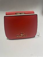 Front view of coral Céline Dion wallet showing gold-tone bow clasp and logo