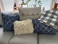 Full view of four pillows and buffalo-check blanket on sofa