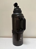 Front view of black Manna stainless steel travel bottle showing flip-top spout and handle