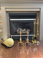 Full lot showing log holder, pair of andirons, tool stand with tools in front of fireplace