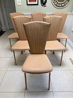 Front view of six matching tan leather dining chairs